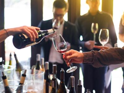 Degustazione di vino con persone che assaporano e versano bicchieri.