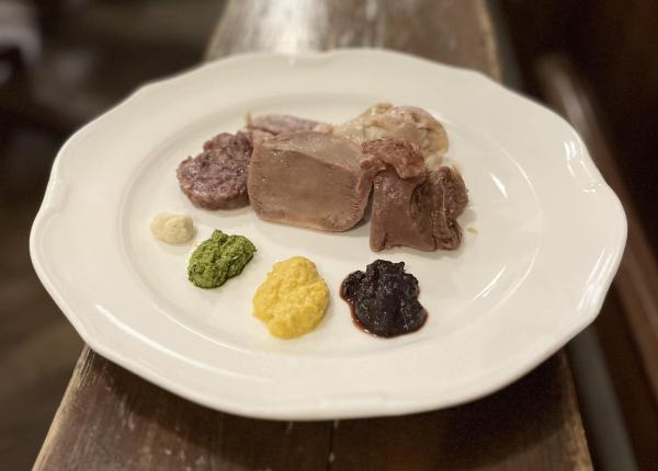 Piatto di carne con salse colorate su piatto bianco.